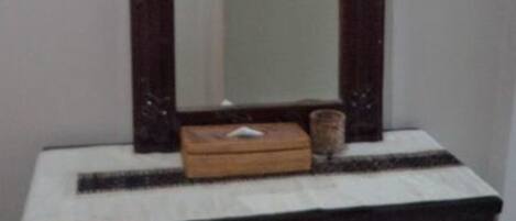 Un tocador pequeño de madera oscura con espejo, una mesita y un banco.