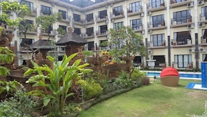 Un hôtel à plusieurs étages doté de balcons, d’une piscine et d’une végétation luxuriante.