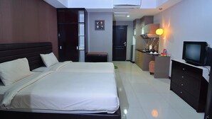 Une chambre d’hôtel avec un grand lit, un bureau équipé d’un ordinateur, une télévision et une kitchenette.