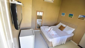 Une chambre d’hôtel avec un lit, un petit bureau, un appareil de climatisation et un miroir.