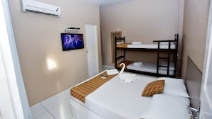 Une chambre d’hôtel équipée d’un lit simple, d’un lit superposé, d’une télévision et d’un appareil de climatisation.