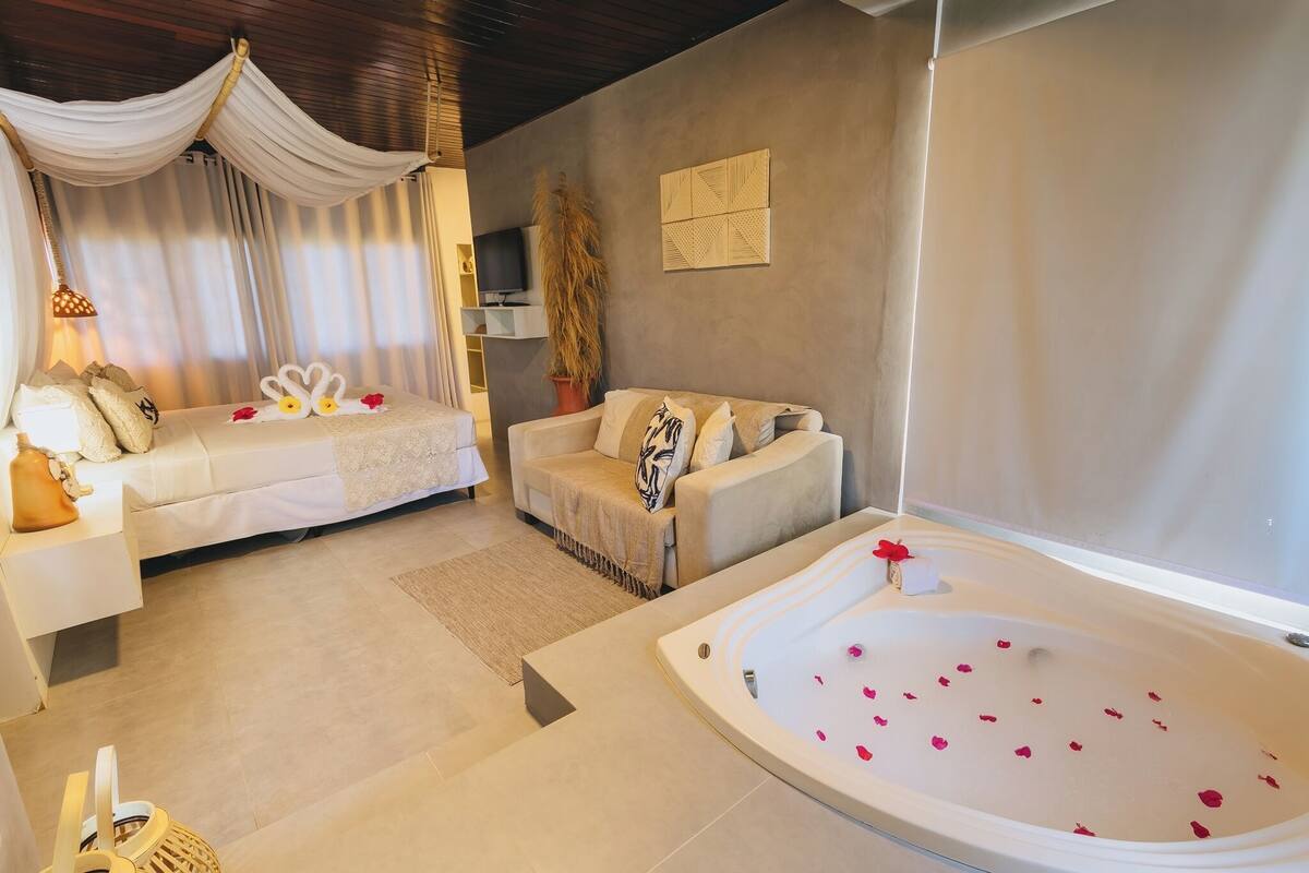 Een moderne spa-ruimte met een groot ligbad, twee banken en een televisie.