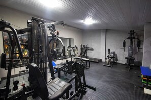 Ein Fitnessstudio mit verschiedenen Trainingsgeräten, Bänken und einer Spiegelwand.