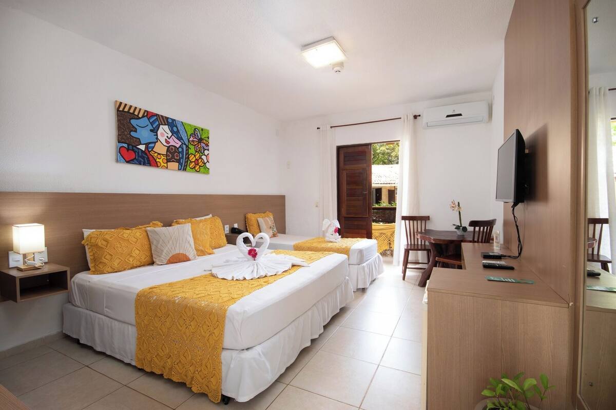 Een hotelkamer met twee bedden, een televisie, een bureau en een schilderij aan de muur.