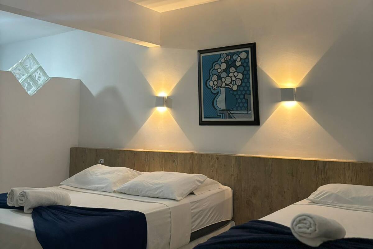 Ein Hotelzimmer mit zwei Betten, einem Oberlicht und Wandleuchten.