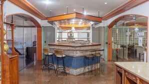 A bar area with a marble countertop, bar stools, and a wooden ceiling. - Praia Hotel Enseada (Maceió)