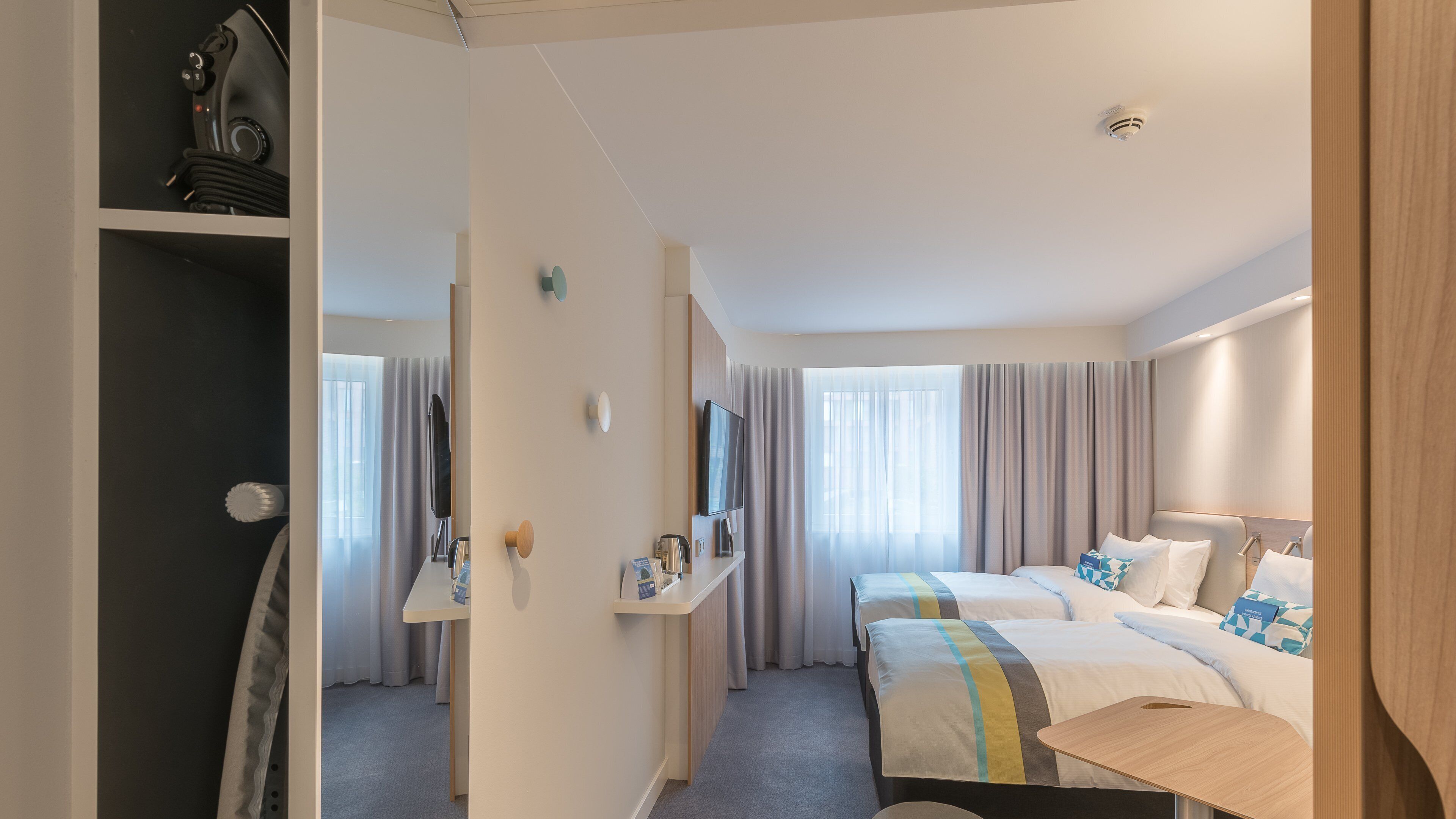 Habitació d'hotel amb dos llits, escriptori, televisió i armari.