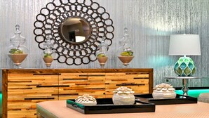 Une chambre à coucher avec une tête de lit en bois, un miroir rond, des vases décoratifs, une lampe et un plateau contenant des objets décoratifs.
