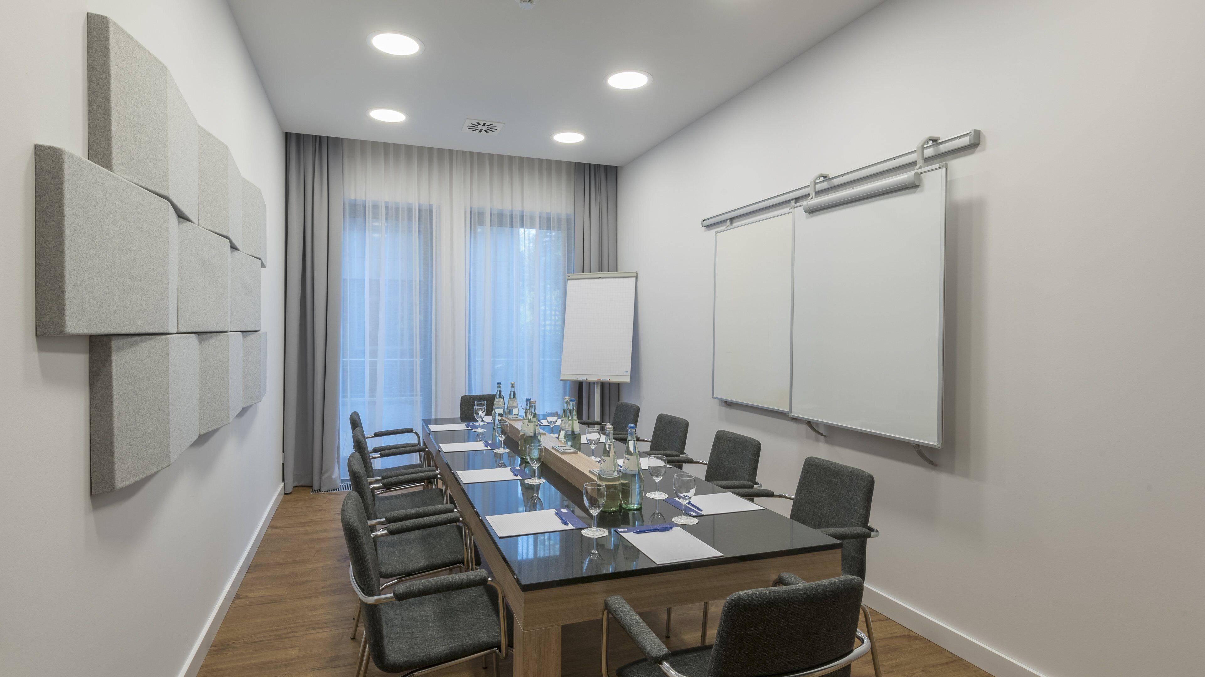 A conference room with a long table, chairs, a projector screen, and a whiteboard.