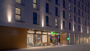 L’entrée d’un hôtel avec une façade en verre, un banc à l’extérieur et une enseigne indiquant « Holiday Inn Express ».