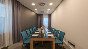 A conference room with a long table, blue chairs, and a modern ceiling design.