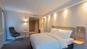 Une chambre d’hôtel comprenant un lit, un bureau, une chaise et une table de chevet.