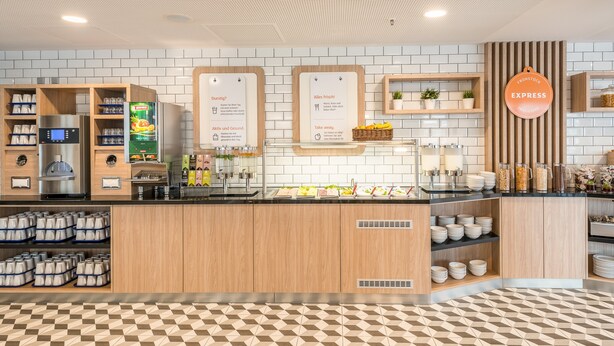 Un café moderne avec un sol à carreaux, des meubles en bois, une machine à café et un panneau indiquant un service « express ».