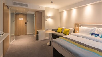 Una habitación de hotel con cama, sofá, una mesita y escritorio.