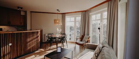 Una sala de estar moderna con una mesa de comedor de madera, un sofá y una zona de cocina con armarios de madera y un banco empotrado.