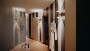 A hotel hallway with striped walls, a robe hanging on a rack, and a towel rack. - Villa Usedom (Heringsdorf)