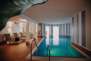 Una piscina techada, sillones reclinables de piscina