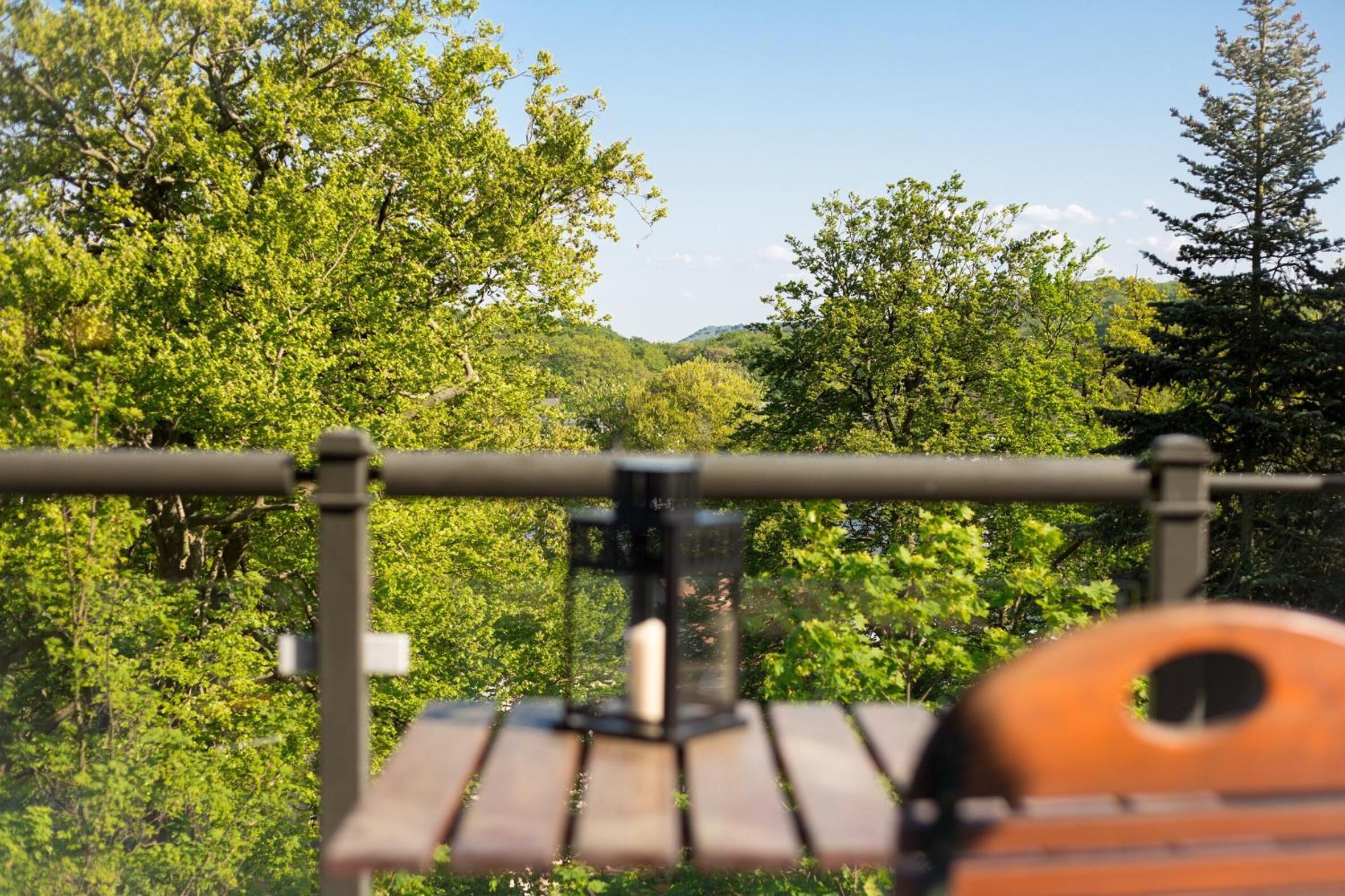 A wooden bench with a metal railing in a forested area.