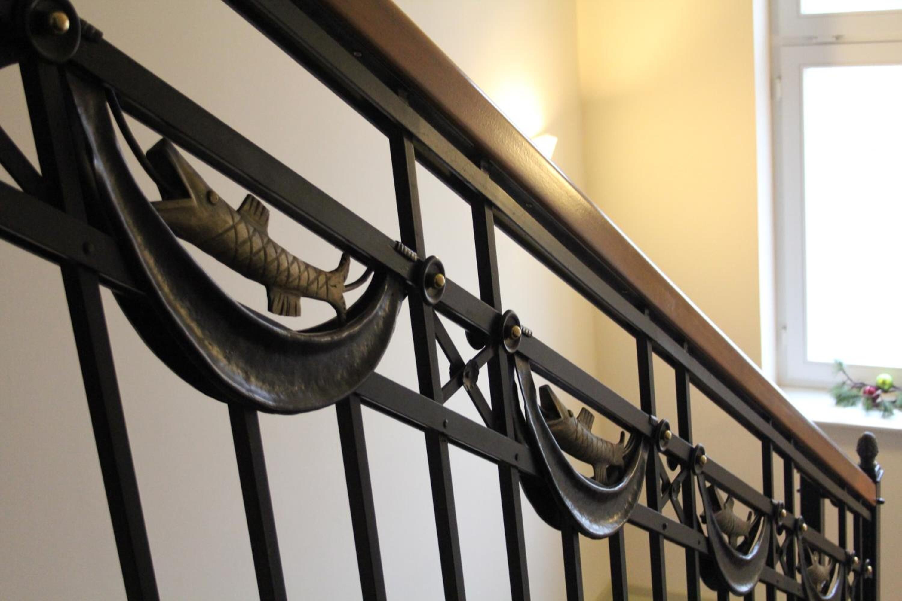 A staircase with a metal railing featuring decorative animal-shaped handles.