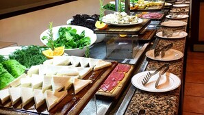 Un bufé con diversas opciones de comida, incluyendo quesos, carnes y verduras.