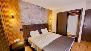 Habitación de hotel moderna con una cama grande, paneles de madera en una pared y una pieza de arte con textura sobre la cama.