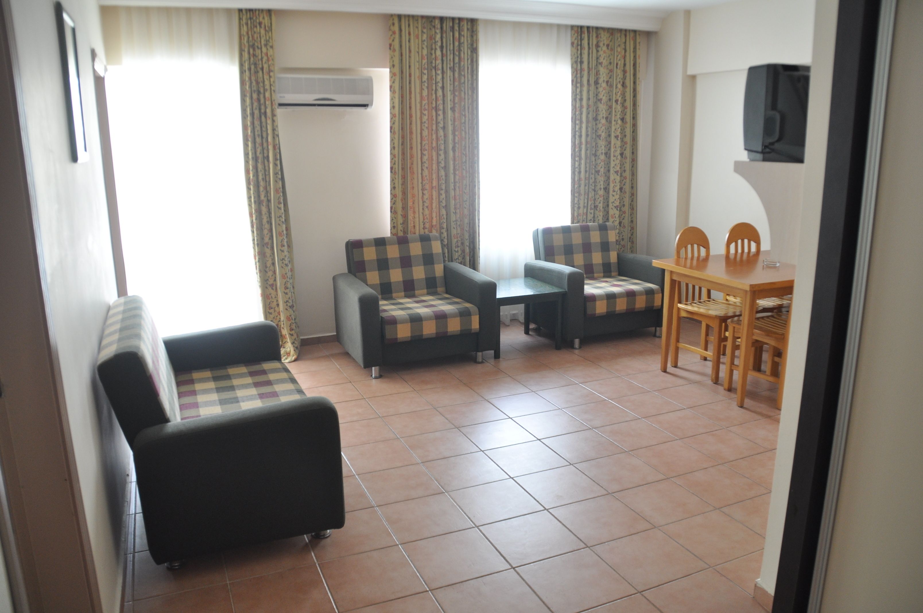 A room with a sofa, two armchairs, a small table, and a dining table with chairs.