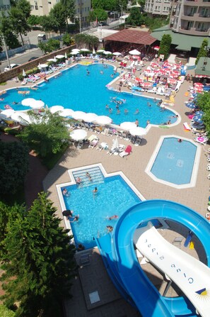 Una amplia piscina al aire libre con varias pistas de natación, rodeada de sillas de descanso y sombrillas.