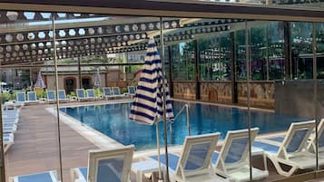 Ein Poolbereich mit Liegestühlen und einem Streifen-Sonnenschirm.