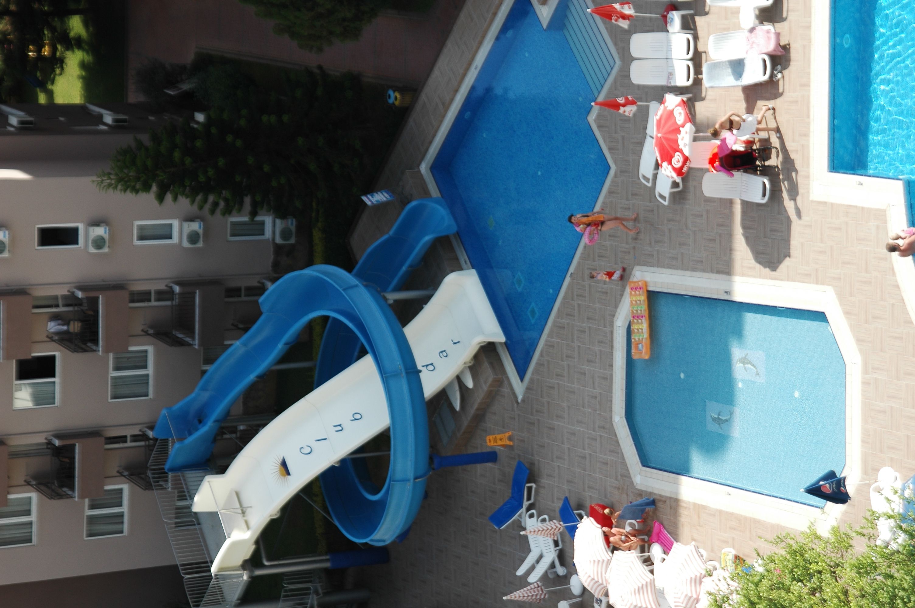A rooftop pool area with a blue slide, lounge chairs, and a small pool.