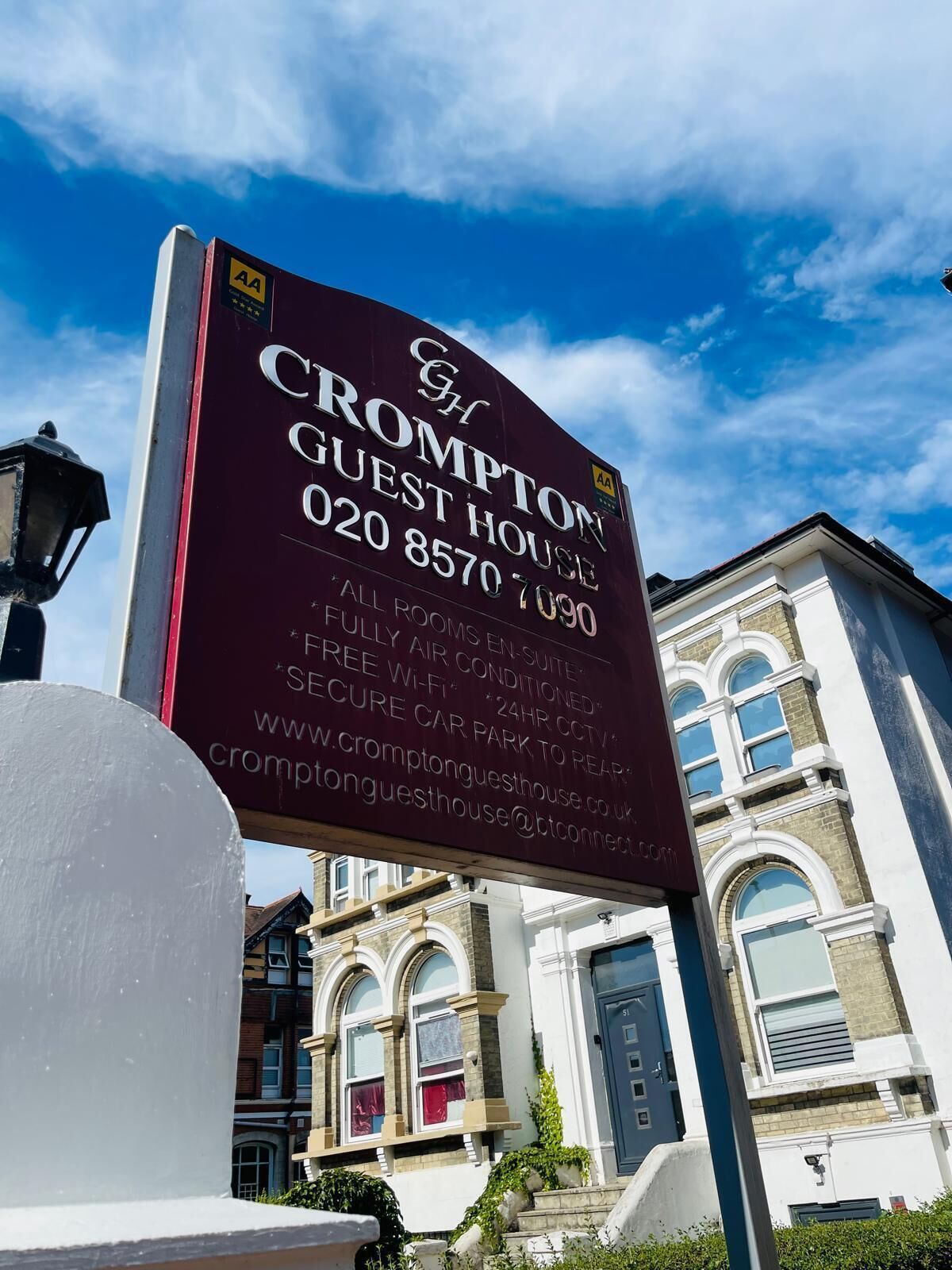 A sign for Crompton Guest House with contact details and amenities listed.