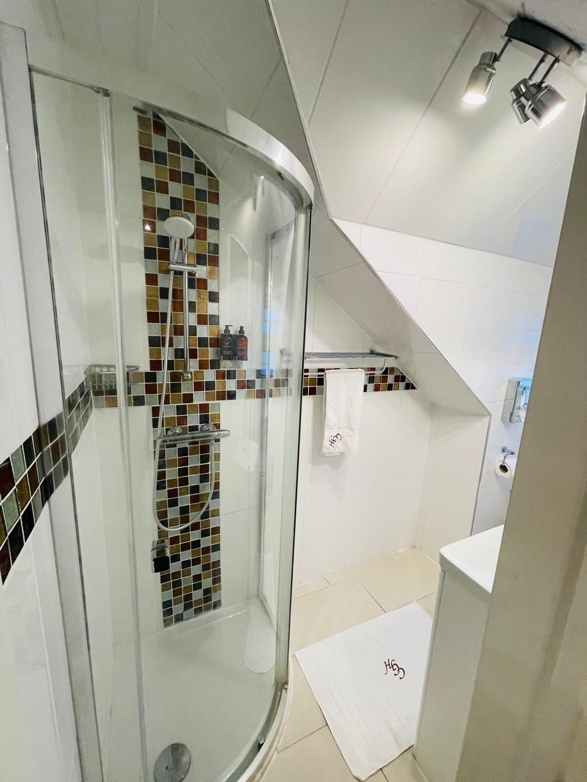 A modern bathroom with a glass-enclosed shower, tiled walls, and a white sink.