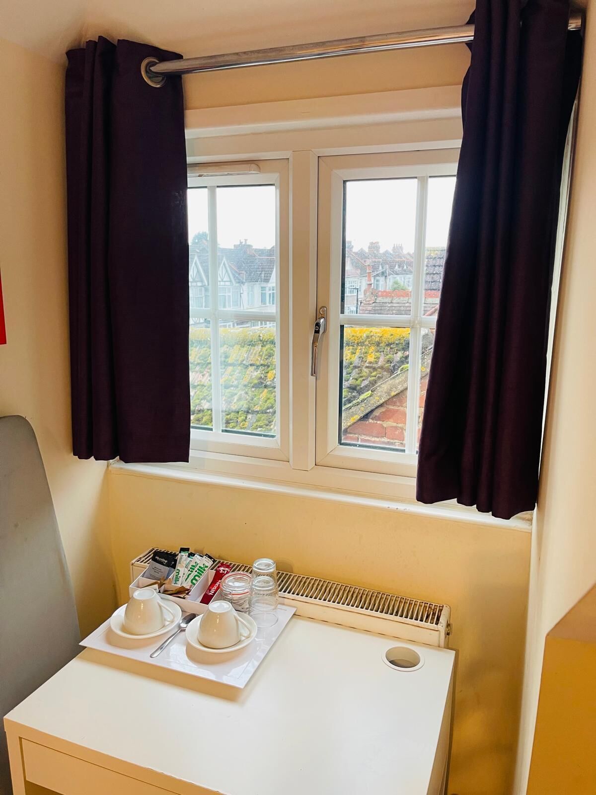 A room with a window, a radiator, and a table with a tea set.