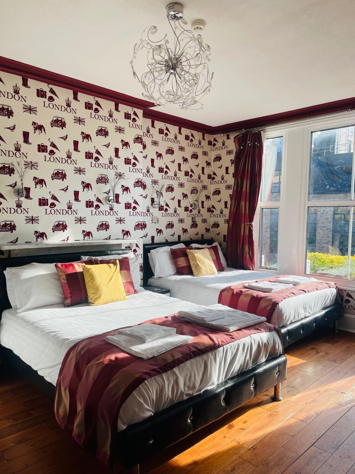 A hotel room with two beds, a chandelier, and a view of the outside.