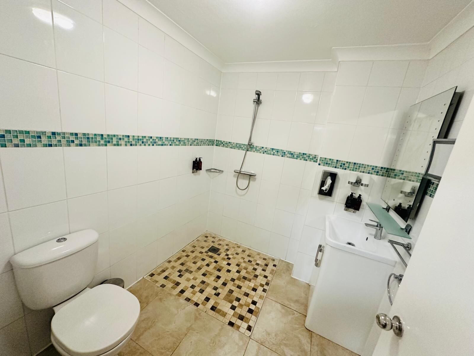 A bathroom with a toilet, a shower, and a sink.