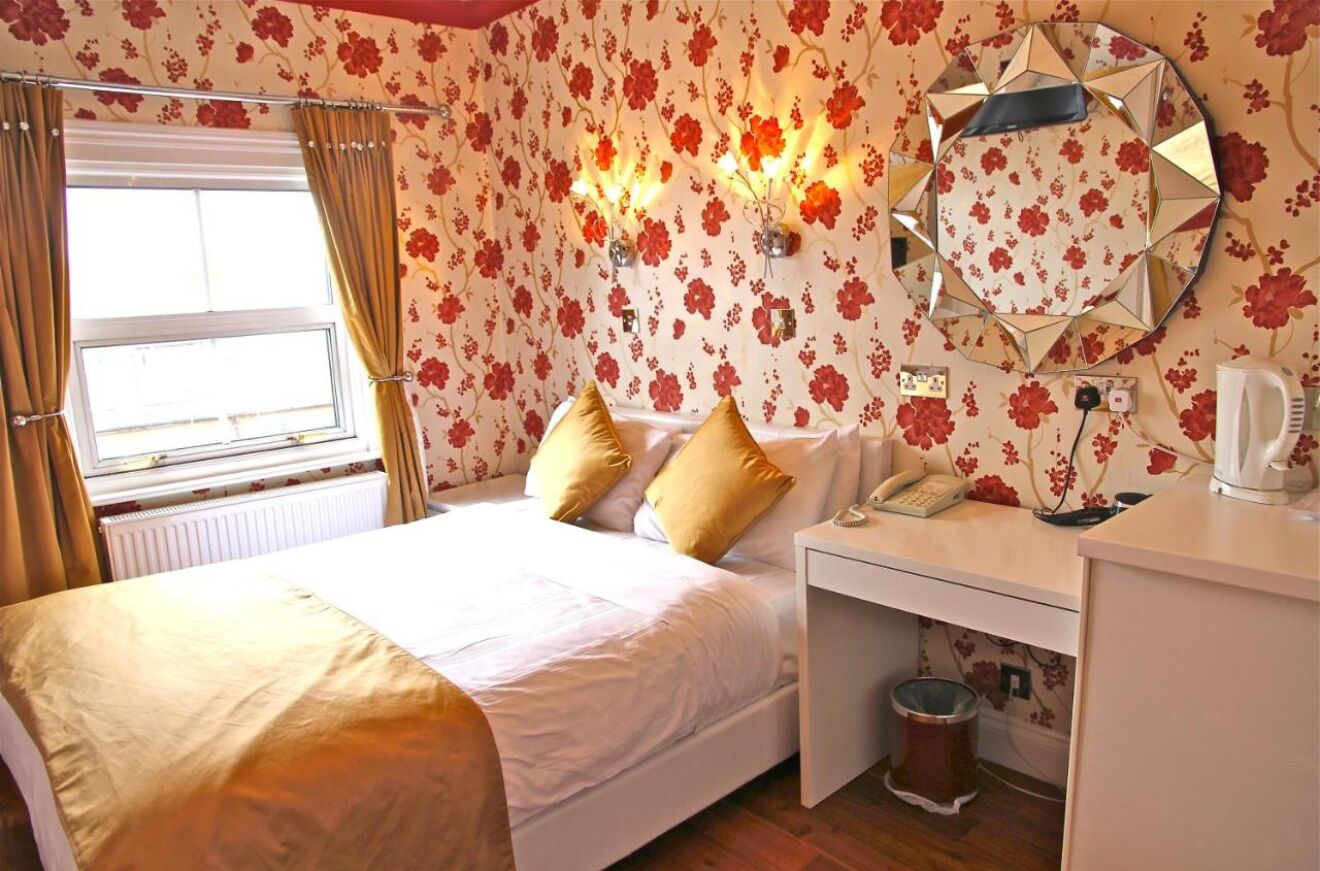 A hotel room with a bed, a desk, a telephone, and a mirror.