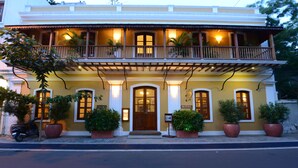 Un hôtel de deux étages doté d’un balcon, de grands pots de plantes et d’une enseigne indiquant qu’il s’agit d’un hôtel.