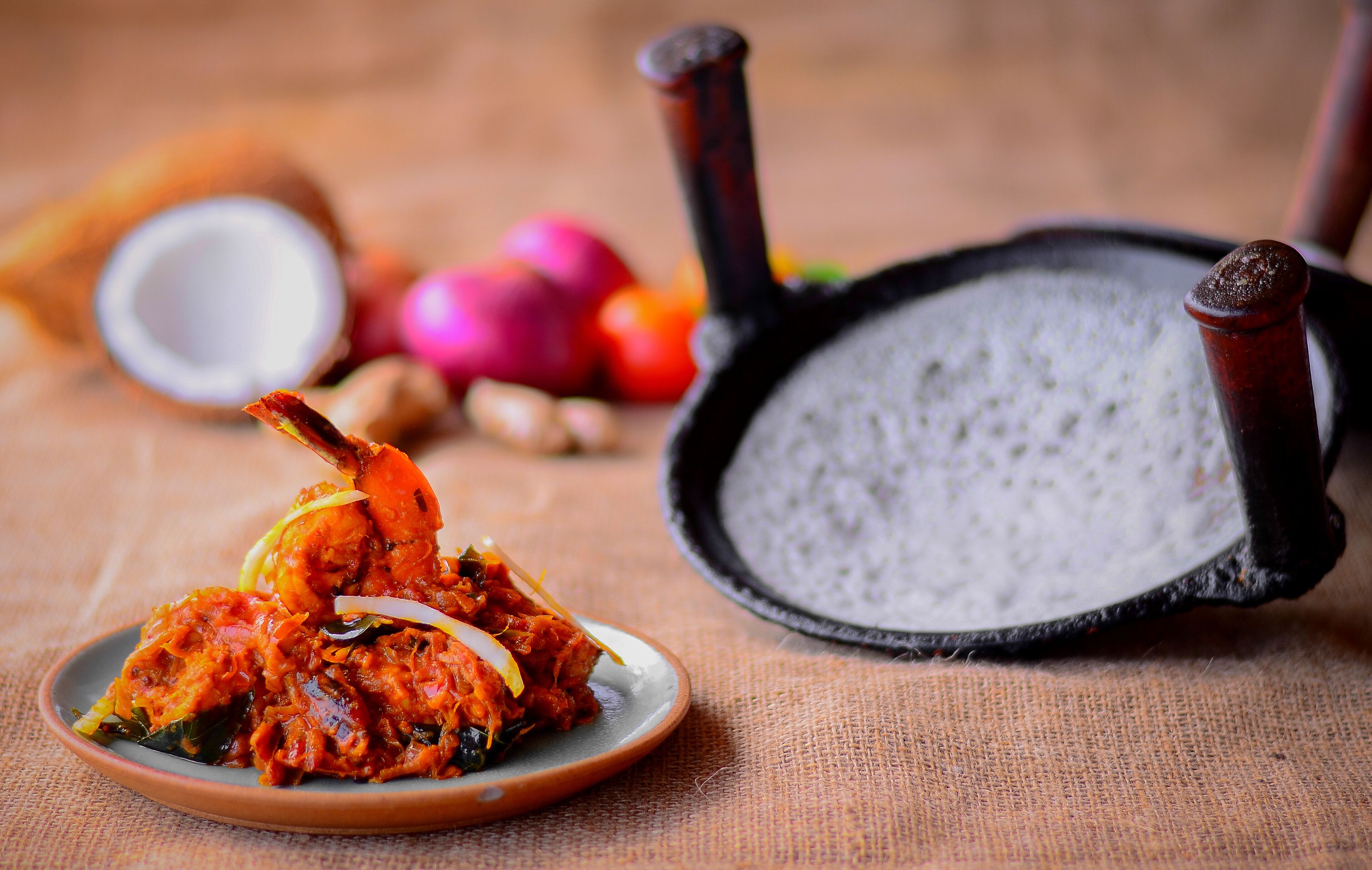 A plate of food with a frying pan and a bowl in the background.