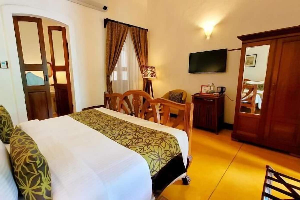 Une chambre d’hôtel comprenant un lit, un bureau, une chaise, une télévision et une armoire.