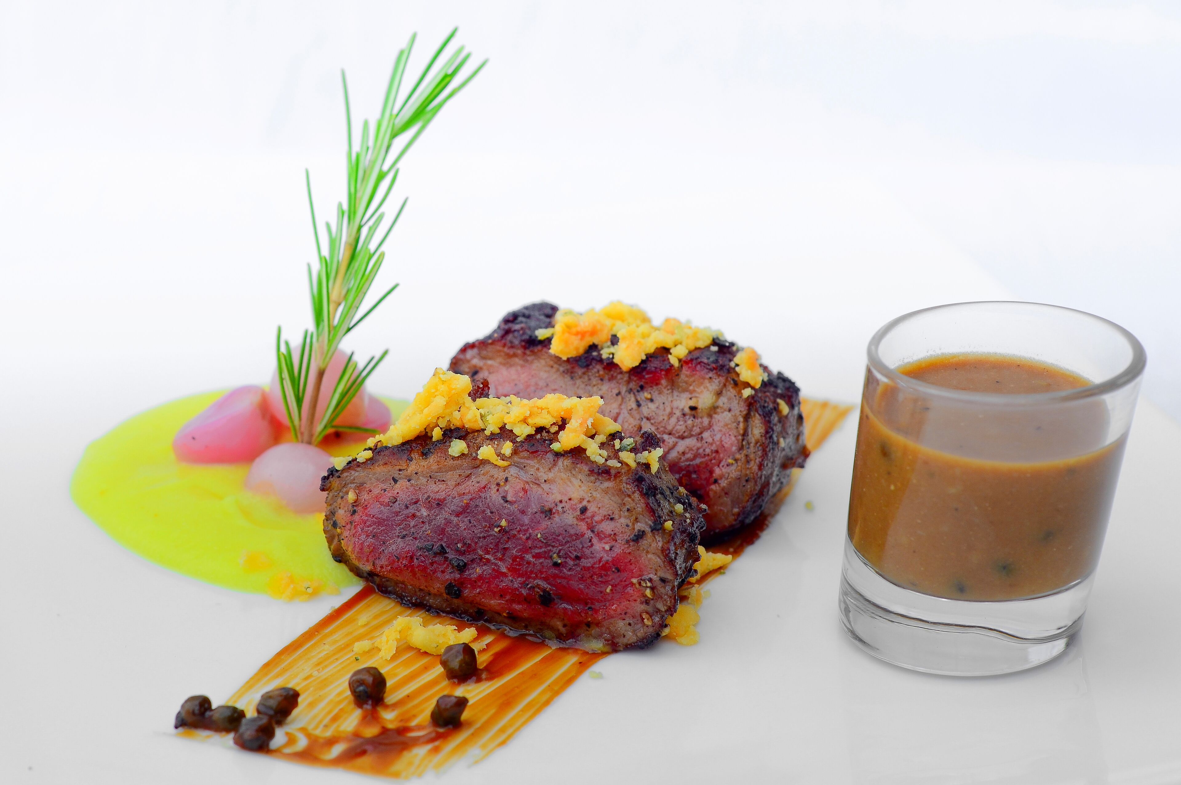 Un plato con un filete, decoración y salsa.