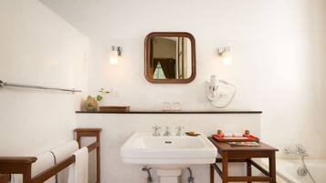 A bathroom with a white sink, a wooden vanity, a mirror, and a bathtub.