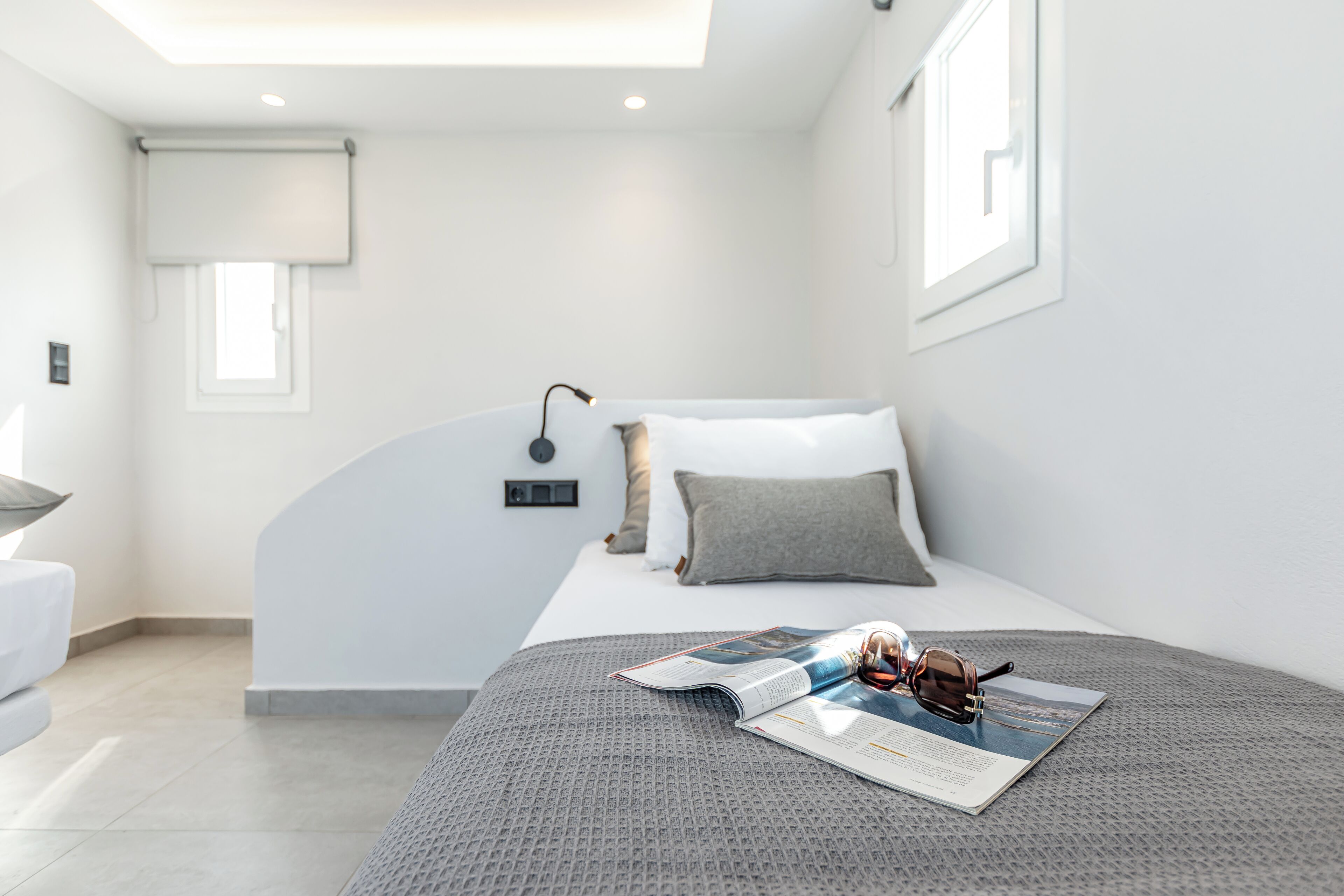 A modern bedroom with a neatly made bed, a bedside table, and a magazine on the bed.