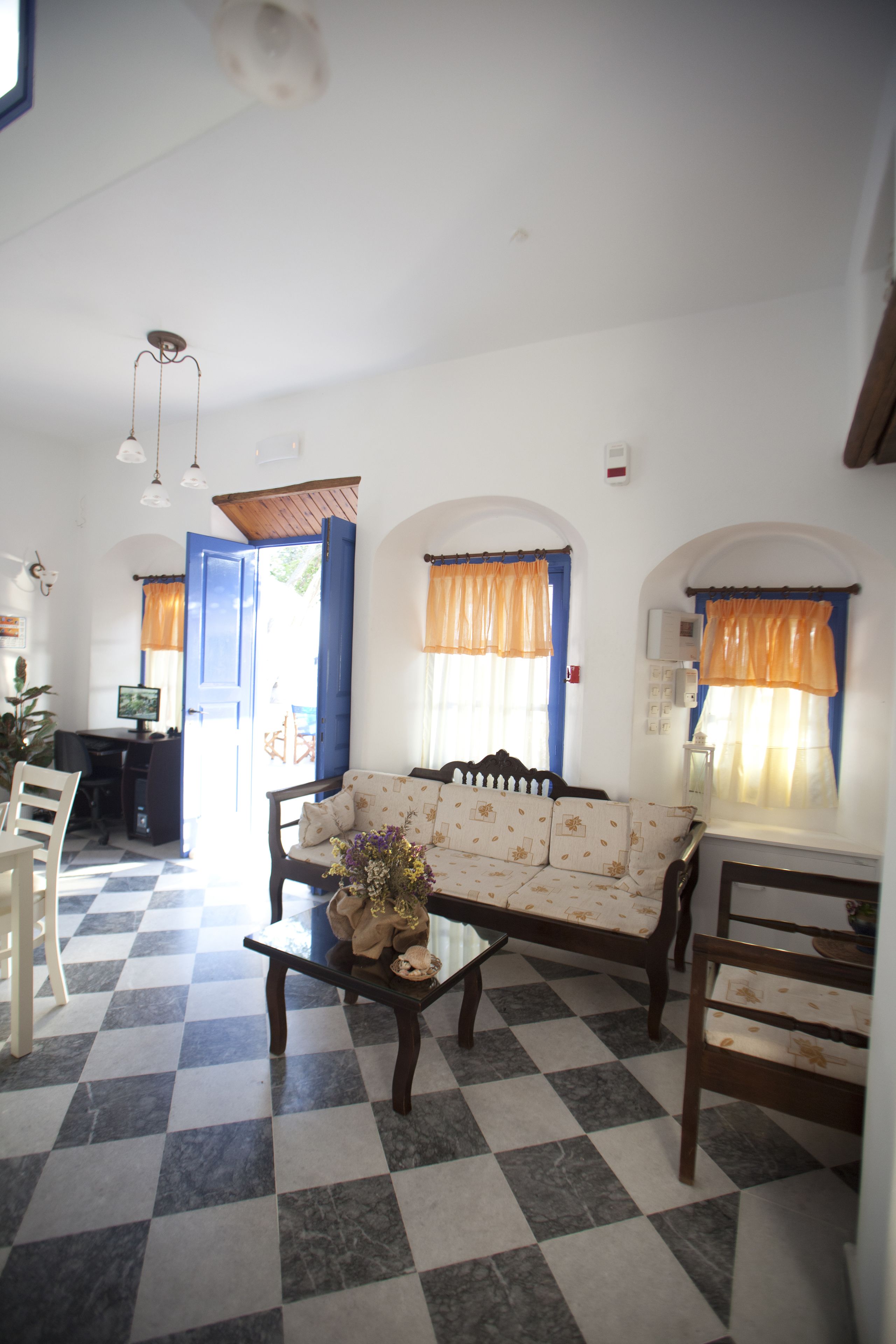 A living room with a checkered floor, a sofa, a coffee table, and a dining area with chairs.