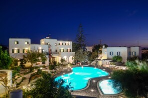 Un hotel moderno con piscina, asientos al aire libre y un patio bien iluminado.