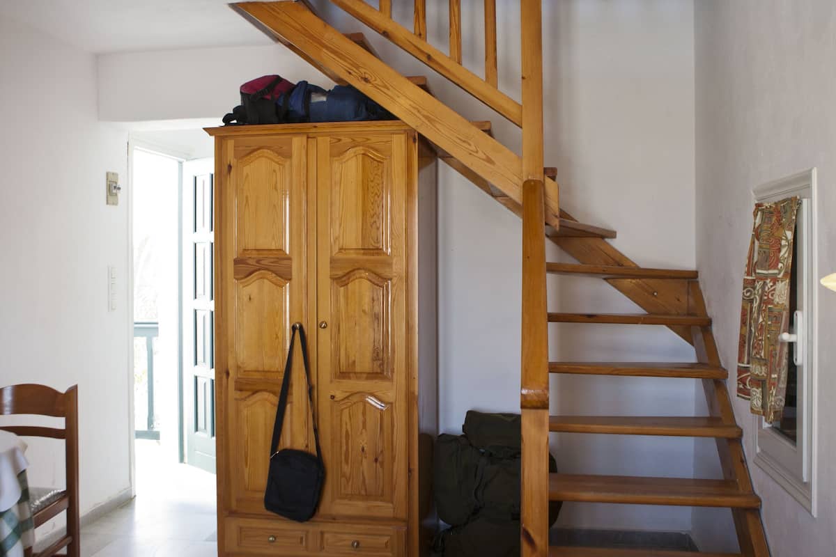 Ein Zimmer mit einer Holztreppe, einem Kleiderschrank und einem Bett mit gefalteten Handtüchern.