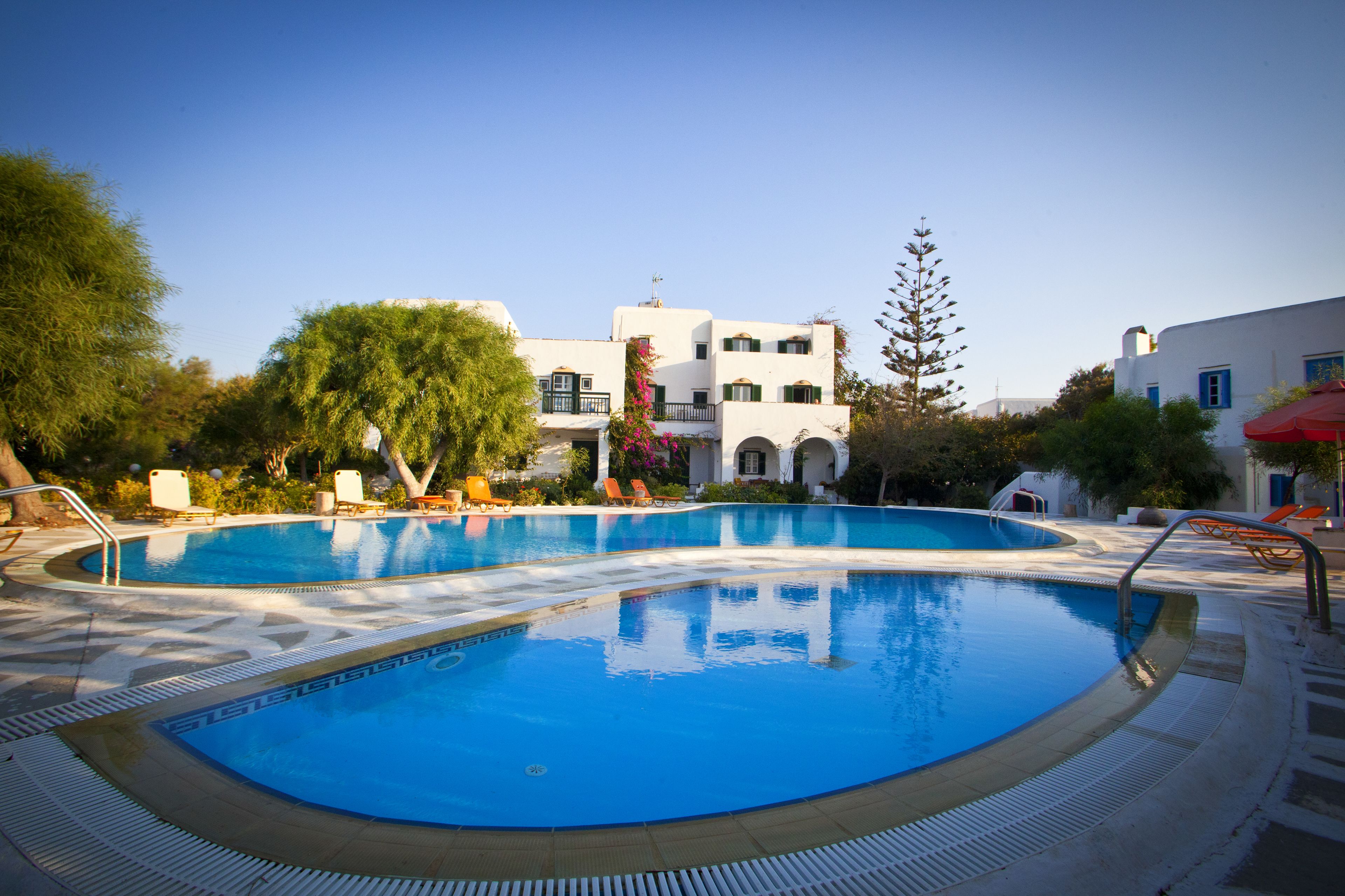Une piscine avec des chaises longues et un bâtiment en arrière-plan.