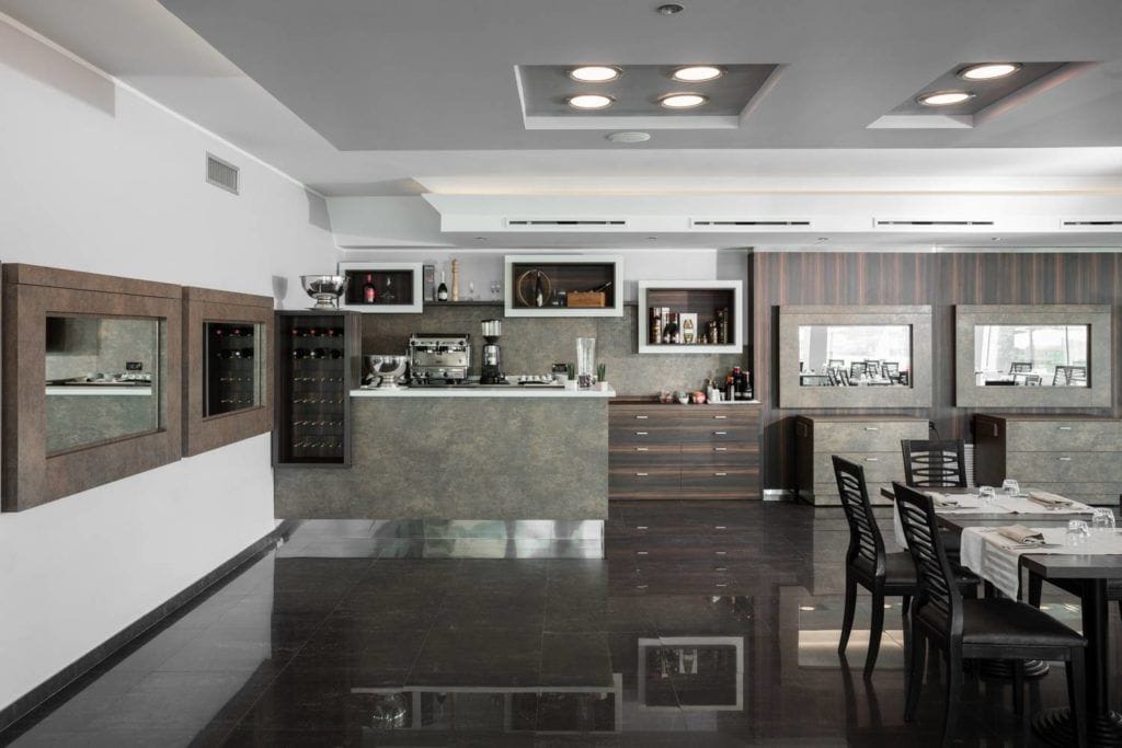 A modern kitchen with a central island, built-in wine racks, and a dining area with a long table and chairs.