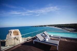A deck with lounge chairs overlooking a pool and the sea. - Hotel Belvedere, Torre Dell'Orso (Melendugno)