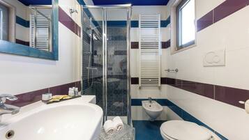 A bathroom with a large sink, a toilet, a bidet, and a glass-enclosed shower.