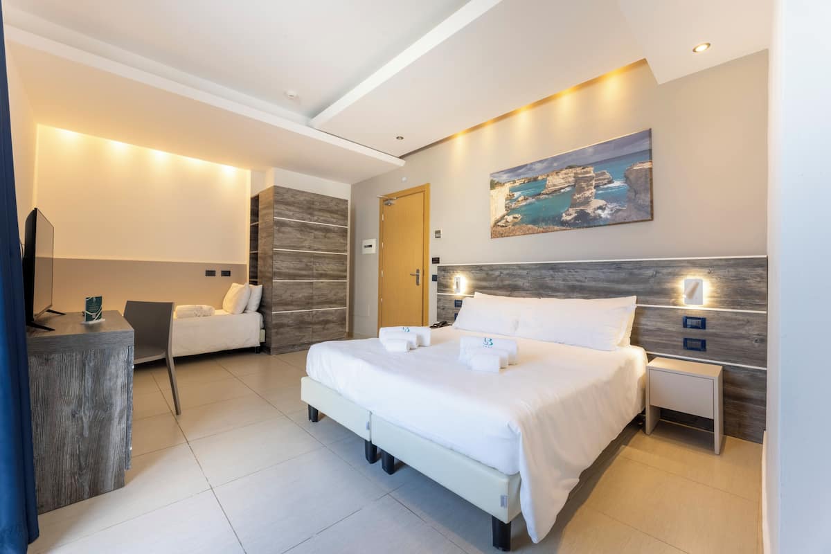 A modern hotel room with a large bed, bedside tables, a desk, and a chair.