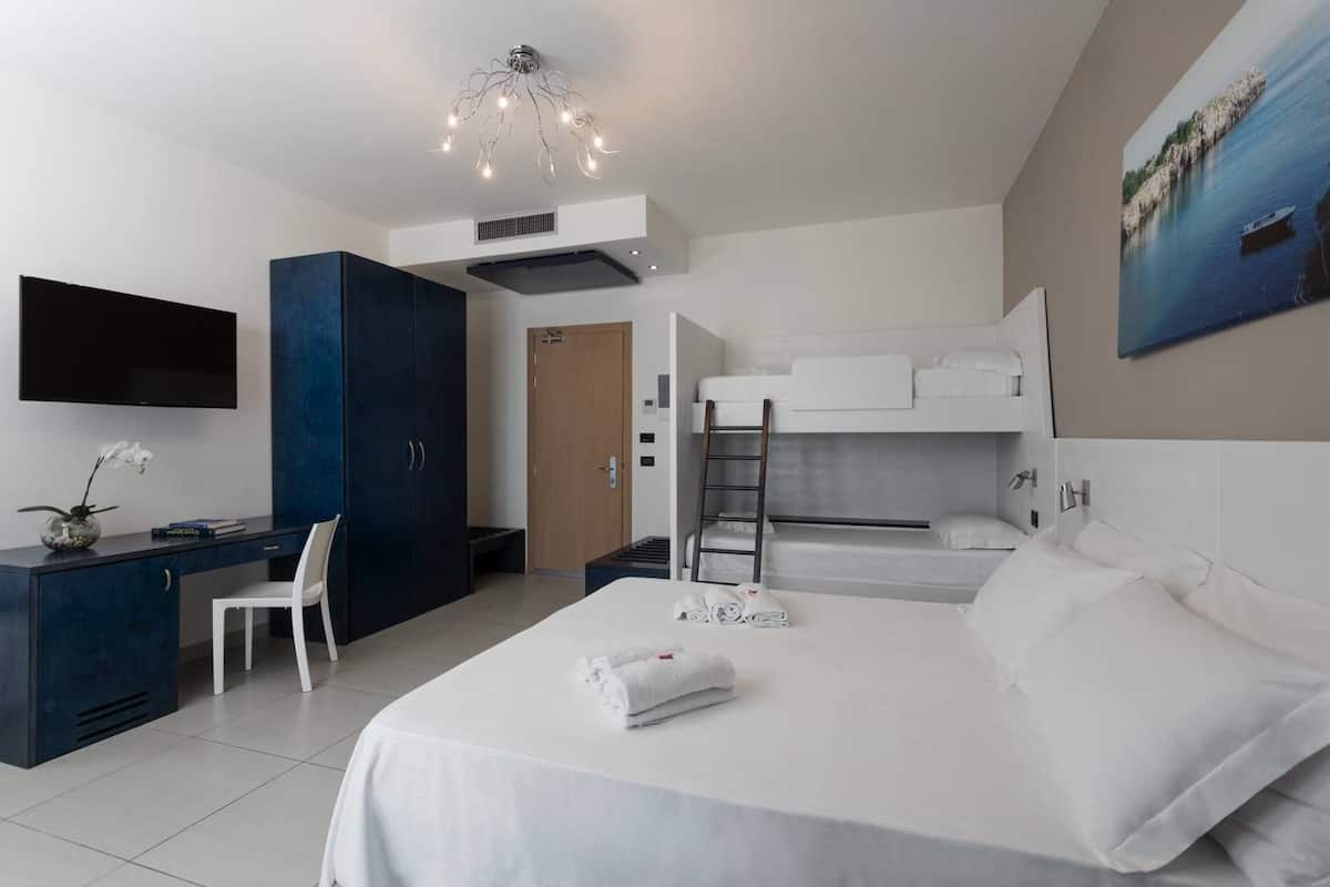 A modern hotel room with a bed, desk, chair, and a TV.
